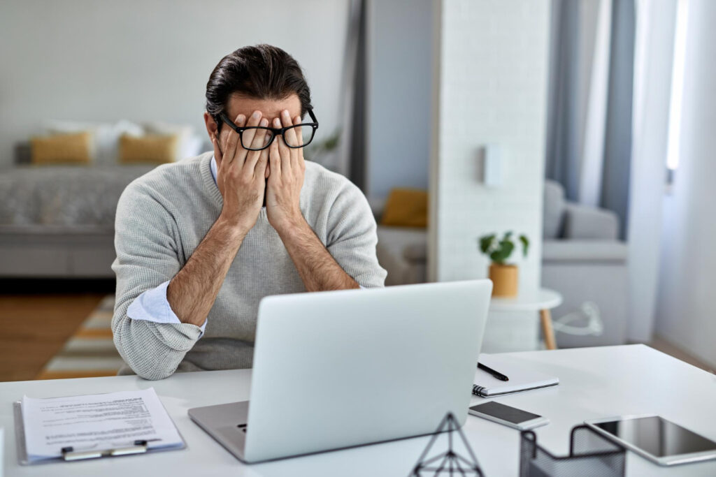 Personne frustrée devant un ordinateur lent nécessitant un dépannage ou une maintenance informatique.